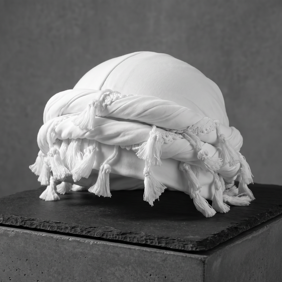 White halo turban with tassels on a slate block, side view