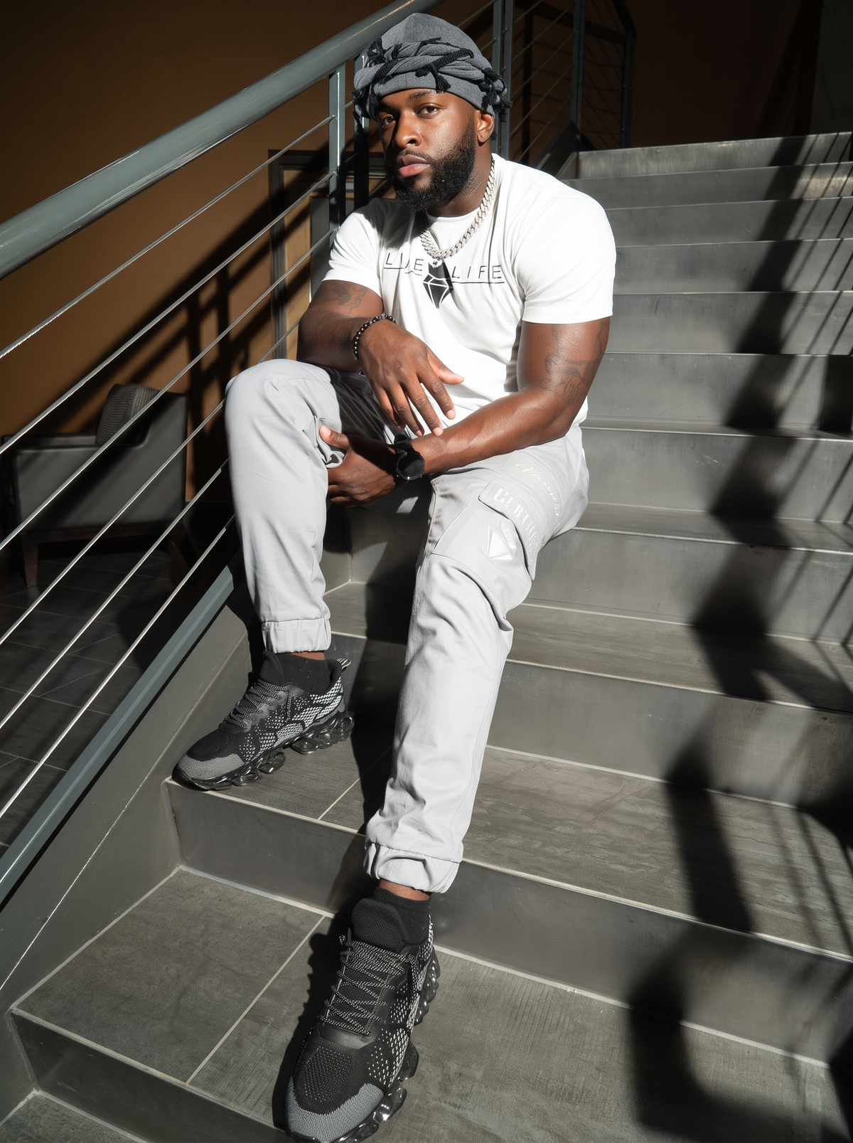 Man wearing the charcoal grey twist turban, seated on stairs in streetwear